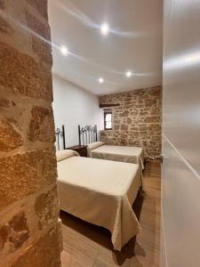Pokój z 3 łóżkami i kamienną ścianą w obiekcie La casa del castillo w mieście Baños de la Encina