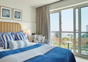 a bedroom with a blue bed and a balcony at St Brides Spa Hotel & Village Apartments in Saundersfoot