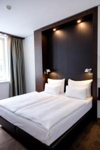 a bedroom with a large white bed with a black headboard at Motel One Prague-Florentinum in Prague
