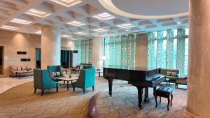 a hotel lobby with a piano and tables and chairs at Emerald Garden International Hotel in Medan