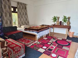 a room with a bed and a table and some rugs at Nanda rawat Homestay in Munsyari