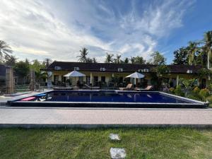 a large swimming pool in front of a house at Kuta Lodge Homestay in Kuta Lombok