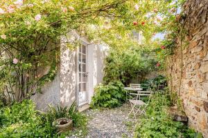 a garden with a table and a window and roses at Le petit logis in La Châtaigneraie