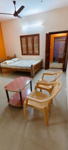 a room with two beds and a table and chairs at Sri Annai Home Stay III in Tiruvannāmalai