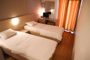 a hotel room with two beds and a desk at Hotel Nora in Zajmovo