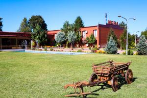 a wooden cart sitting in the grass in front of a building at Hotel Nora in Zajmovo