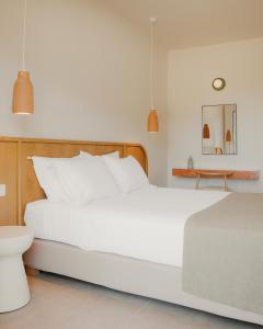 a bedroom with a large white bed and a table at Hotel Apollon Corfu in Paleokastritsa