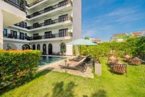 a house with a pool and a table and an umbrella at Hoi An Delicacy Hotel & Spa in Hoi An