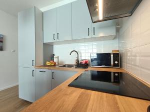 Una cocina con gabinetes blancos y un microondas. en Apartament Baltic Sauna Break e-apart, en Władysławowo