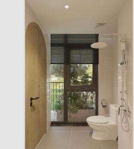 a bathroom with a toilet and a window at Grand Central Hotel- Vinhomes Ocean Park 3 in Ðình Loan