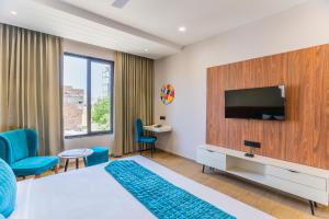 a hotel room with a bed and a flat screen tv at The Aureum-A Unit of Sandy Blossom in Udaipur