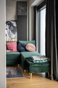 a living room with a green couch and a ottoman at The Final Countdown in Katowice