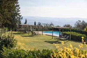 a garden with a pool and a group of chairs at Il Villino Farmhouse in Castellina in Chianti