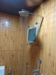 ein Badezimmer mit Dusche und einem Fernseher an der Wand in der Unterkunft Tiri Ratna Cottage in Jāmb