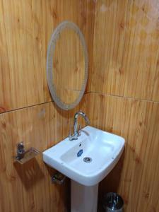 ein Badezimmer mit Waschbecken und Spiegel an einer Holzwand in der Unterkunft Tiri Ratna Cottage in Jāmb