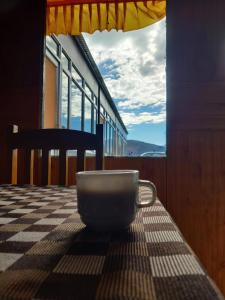 eine Schüssel auf einem Tisch mit einem Fenster in der Unterkunft Tiri Ratna Cottage in Jāmb