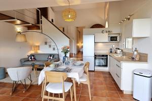 a kitchen and living room with a table and chairs at Sous le Pin - Villa paisible face aux îles Lavezzi in Bonifacio