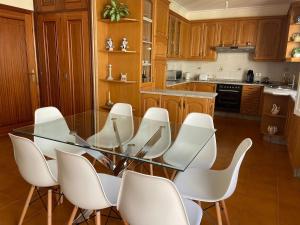 a kitchen with a glass table and white chairs at Villa Playa Raxó in Raxó