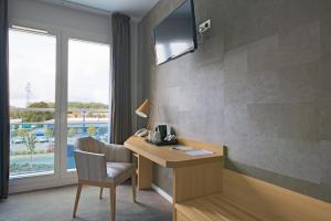 a room with a desk with a chair and a television at Le Konine - Hotel & Bar & Restaurant in Montceau-les-Mines