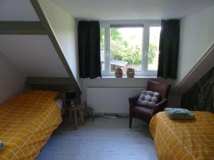 a bedroom with two beds and a chair and a window at het Uitzicht in Elspeet +28 photos