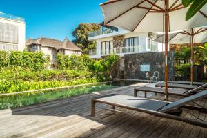 a swimming pool with two lounge chairs and an umbrella at Soma Bay - Incredible Seaside Apartment in Tamarin