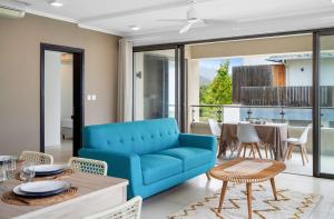 a living room with a blue couch and a table at Soma Bay - Incredible Seaside Apartment in Tamarin +31 photos