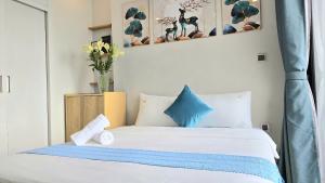 - une chambre avec un lit blanc aux accents bleus dans l'établissement Vinhomes Greenbay Studio Luxury Apt #Jerry's House, à Hanoï