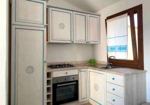 a kitchen with white cabinets and a sink and a stove at Wind Rose Exclusive -Natural pool 50 m from the Sea in Olbia