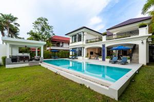 an exterior view of a house with a swimming pool at Villa Viola 7 Bedroom, Fully Staffed, on the Golf Course in Laguna Phuket