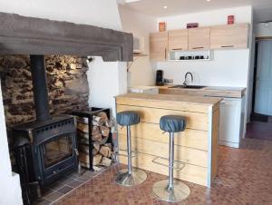 a kitchen with a stove and two bar stools at Maison du bourg in Mayres
