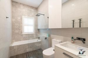 Un baño con bañera, inodoro y lavabo. en KozyGuru | Rose Bay | 3BR Steps to Beach + Parking, en Sídney 11 fotos más