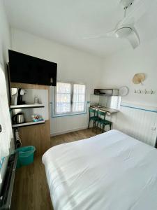 a bedroom with a white bed and a table at Hotel Oasis in Argelès-sur-Mer