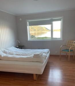 a bedroom with a bed with a window and a chair at Seljesanden Apartment in Selje