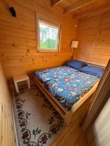 a bed in a log cabin with a window at Na Piaskach Agroturystyka Domek pod Lipą in Narol