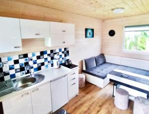 a kitchen with a couch in a tiny house at Domki Letniskowe SOHO in Bobolin
