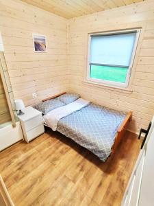 a bedroom with a bed and a window at Domki Letniskowe SOHO in Bobolin
