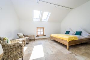 a bedroom with a bed and two wicker chairs at Hofgut Dösterhof - Hotelzimmer in Wadern