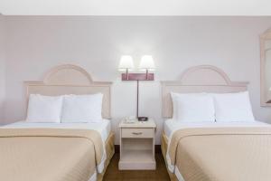 a hotel room with two beds with white pillows at Days Inn & Suites by Wyndham Navarre - near Beaches Hurlburt in Navarre +28 photos