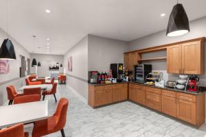 a kitchen with wooden cabinets and a table and chairs at Days Inn by Wyndham Kenner/New Orleans Airport South in Kenner