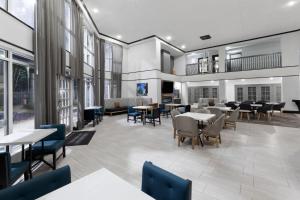 a dining room with tables and chairs and windows at La Quinta Inn & Suites by Wyndham Houston Bush IAH South in Houston