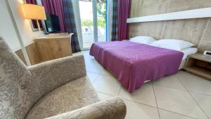 a bedroom with a purple bed and a chair at Hotel Slovenska Plaza in Budva