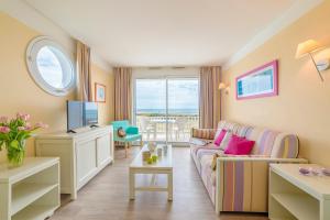 a living room with a couch and a tv at Lagrange Vacances L’Estran in Les Sables-dʼOlonne