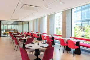 a restaurant with tables and red chairs and windows at nhow Frankfurt in Frankfurt