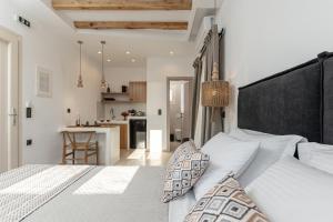 a bedroom with a large white bed and a kitchen at Ruby of Naxos Residences in Kastraki