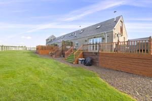 a house with a wooden fence and a yard at JOIVY Greenknowes Cottage with Hot Tub & Fireplace in Kelty