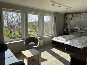 a bedroom with two beds and a chair and windows at Lofoten Bed & Breakfast Reine - Rooms & Apartments in Reine