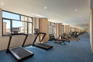 a row of treadmills and exercise bikes in a gym at Ramada by Wyndham Urumqi Midong in Ürümqi