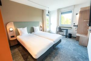 a hotel room with a large bed and a desk at Hôtel AKENA Chalons-en-Champagne in Châlons-en-Champagne