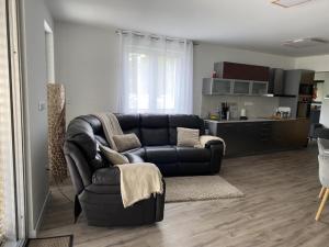 a living room with a black couch and a kitchen at Balatonkenese Sunshine Villa in Balatonkenese