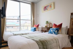 two beds in a room with a large window at Mi-Hotel MIYA Shinjuku 新宿四谷 in Tokyo